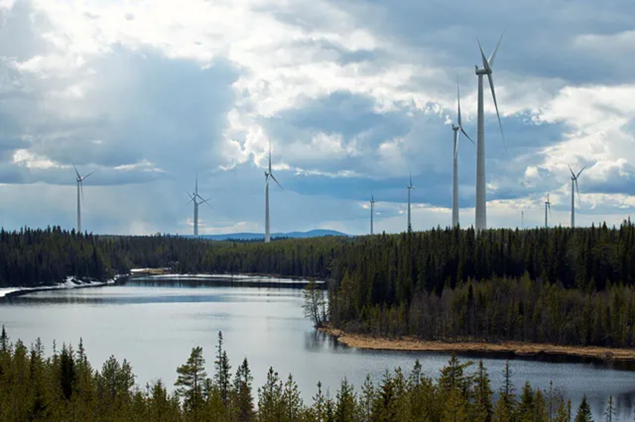 En vid bild över Mörttjänbergets vindkraftpark där ett antal vindkraftverk är synliga mot molnig himmel.