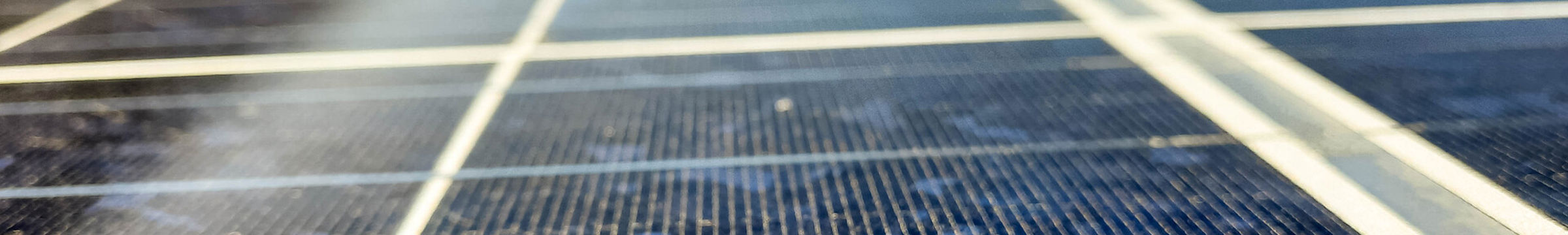 Närbild av solpaneler där solen speglas mot ytan.